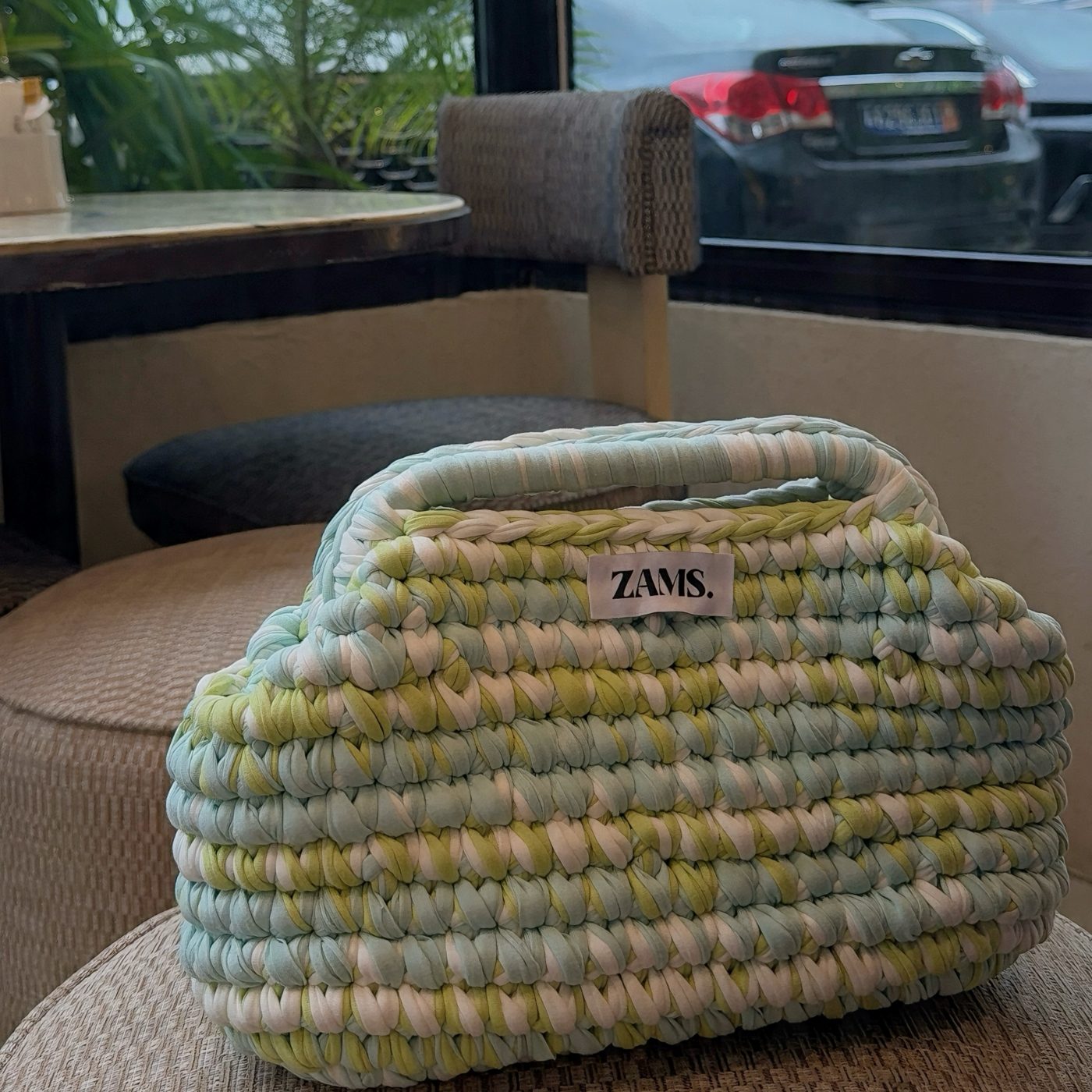 Sac Bestseller crocheté à la main, posé sur un pouf
