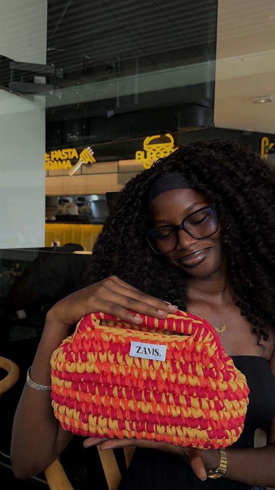 Une cliente serre contre elle son sac ZAMS. rouge, orange et jaune